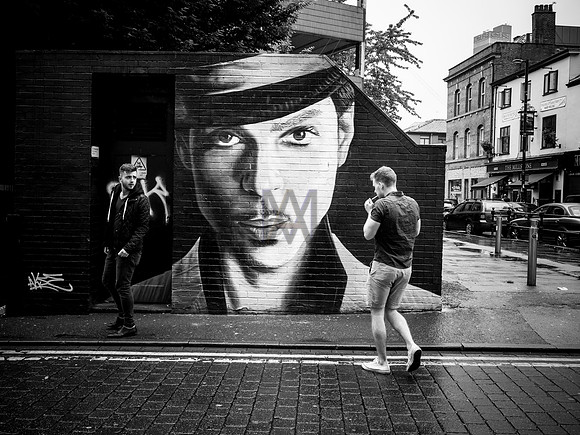 People walk by a street artist's tribute to Prince, by Preston street photographer Alf Myers